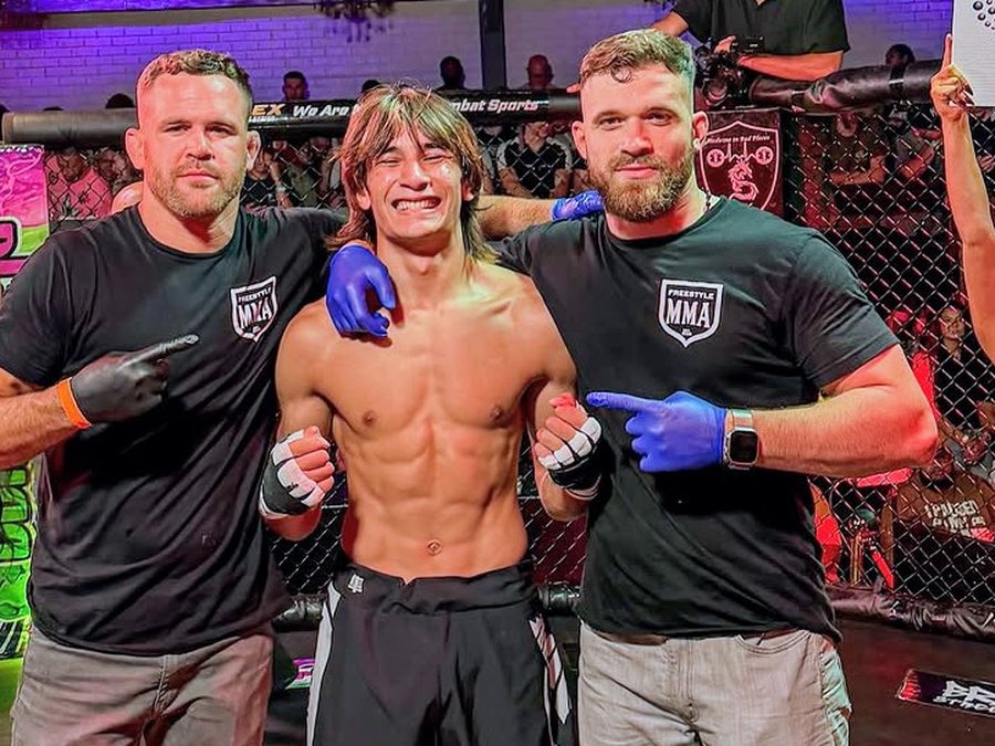 Siam Khamsopa in the cage after a win, flanked by two Freestyle MMA coaches